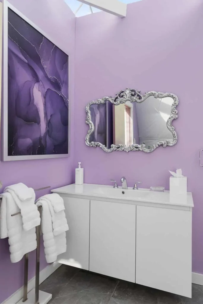 Elegant bathroom with purple walls, ornate mirror, modern sink, and plush towels, reflecting the unique accommodation experience at Escape Velocity Dome.