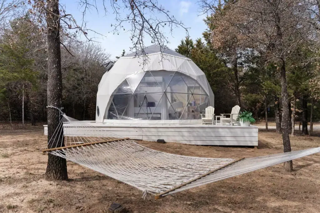 Escape Velocity dome with hammock in a natural setting, showcasing unique geodesic architecture and outdoor relaxation space.