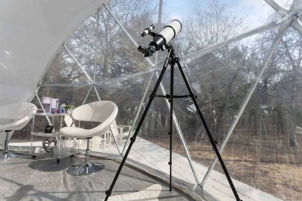 Telescope positioned inside the Escape Velocity dome, featuring modern furnishings and panoramic views of nature.
