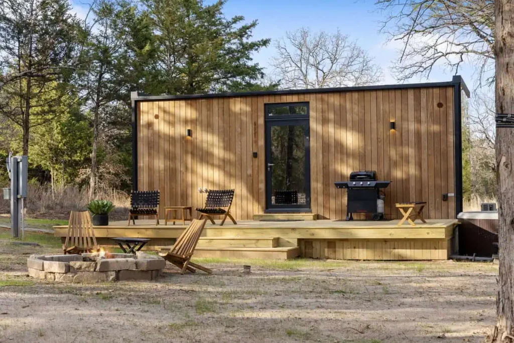 Music Box yurt accommodation at All Is Well Resort featuring a wooden exterior, fire pit, seating area, and propane grill in a natural setting.