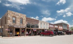 Historic stone and brick storefronts on the main street of Saint Jo, Texas under a blue sky